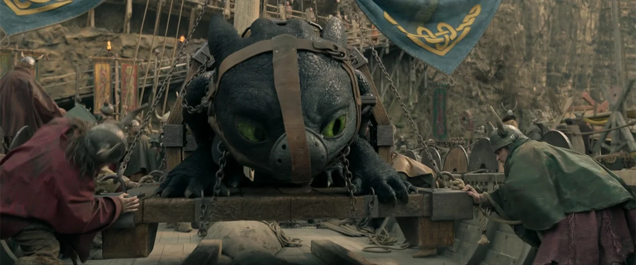 How to Train Your Dragon (2025) movie still: medium — A wooden platform on a stone dock is occupied by a large black dragon. Viking figures in…