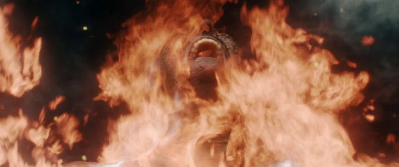 Saint Maud (2019) movie still: closeup — A man's face and upper chest are enveloped in intense, rising flames. The subject tilts his head back with…