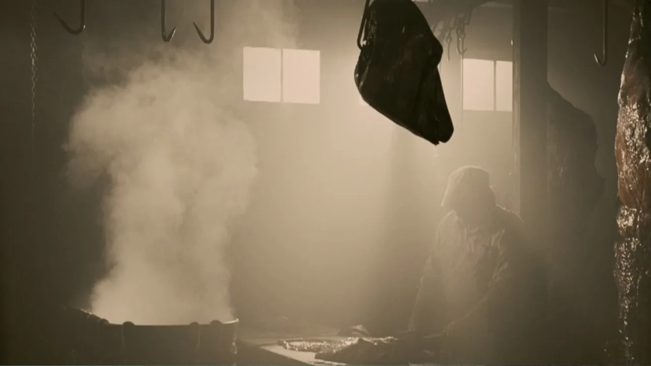 The Texas Chainsaw Massacre: The Beginning (2006) movie still: wide — A dimly lit industrial workspace is filled with thick haze and hanging metal…