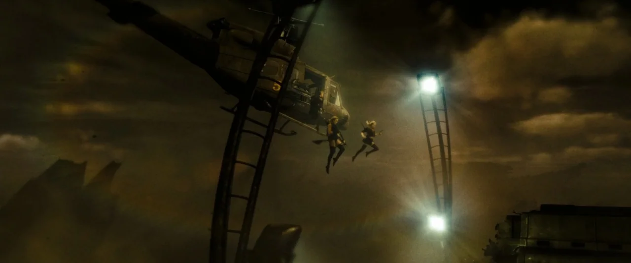 Sucker Punch (2011) movie still: wide — A dark, smoky warzone is illuminated by bright industrial lights fixed to curved poles. Two armed women leap…