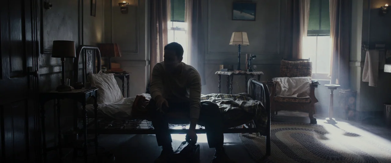 Live By Night (2016) movie still: fullbody — A sparsely furnished mid-century hotel room with heavy drapes and a single bed. A man in dark trousers…