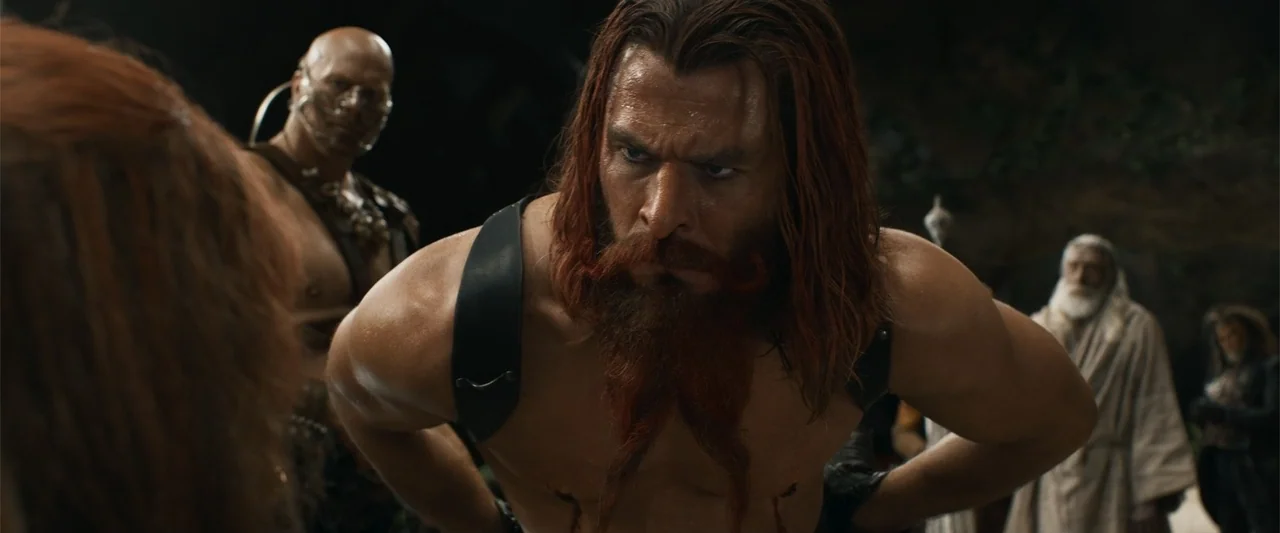 Furiosa: A Mad Max Saga (2024) movie still: medium — A dimly lit cavern interior features rocky walls and dark shadows. A muscular bearded man…
