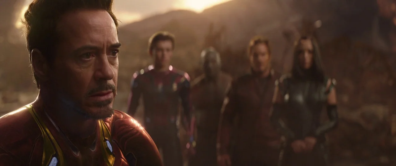 Avengers: Infinity War (2018) movie still: medium — A rocky, barren landscape under a dusky orange sky stretches into the distance. Five individuals…