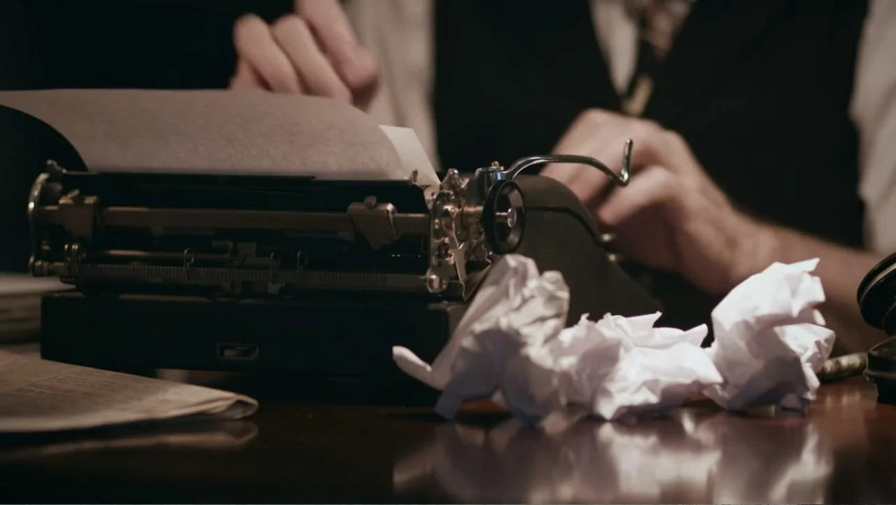 UFO Conspiracies: The Hidden Truth (2020) movie still: medium — A dark wooden desk holds a manual typewriter and several crumpled white paper balls.…