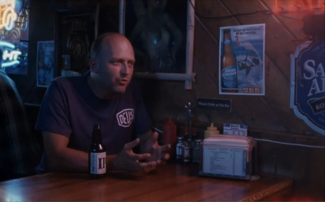 The Greasy Hands Preachers (2014) movie still: medium — A dimly lit bar interior features wooden paneled walls covered in various beverage…