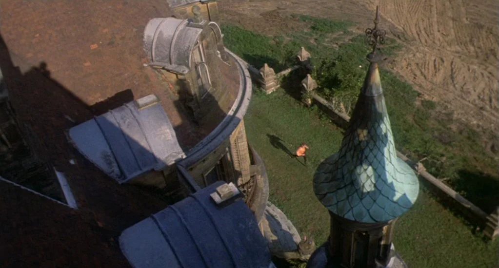 Demons of the Mind (1972) movie still: establishing — The exterior of a grand, multi-storied mansion features tiled roofs and a tall tower. A small…