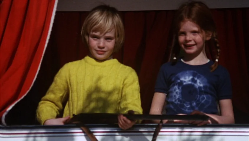 A Bay of Blood (1971) movie still: medium — Two children stand side-by-side behind an open window framed by bright red curtains. The boy in a yellow…