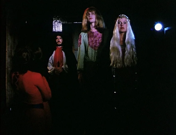 The Niklashausen Journey (1970) movie still: fullbody — A dimly lit interior space with four figures arranged in a line. The subjects stand against…