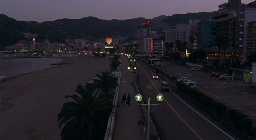 Yi-Yi (A One and A Two) (2000) movie still: establishing — A coastal city is visible at dusk with mountains in the background behind buildings. A…