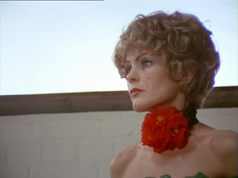 The Bitter Tears Of Petra Von Kant (1972) movie still: closeup — A brightly lit interior space with a white brick wall and plain background. A woman…