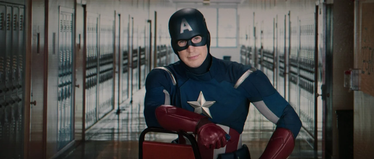 Spider Man: Homecoming (2017) movie still: medium — A long school hallway features rows of gray metal lockers on both sides. A masked superhero…