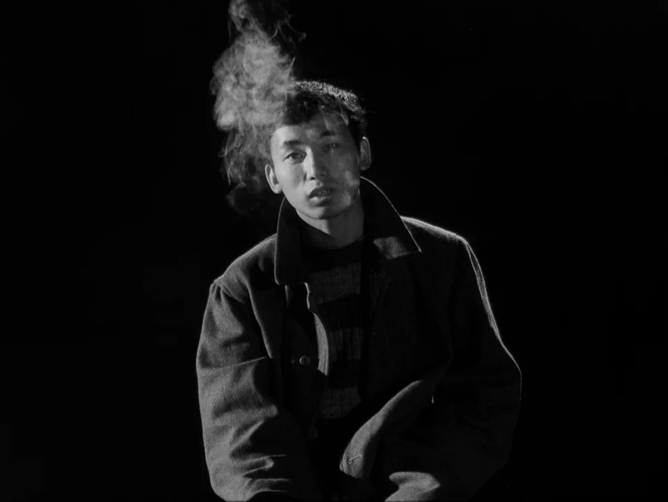 Throw Away Your Books, Rally in the Streets (1971) movie still: medium — A man sits against an entirely black, featureless background that obscures…
