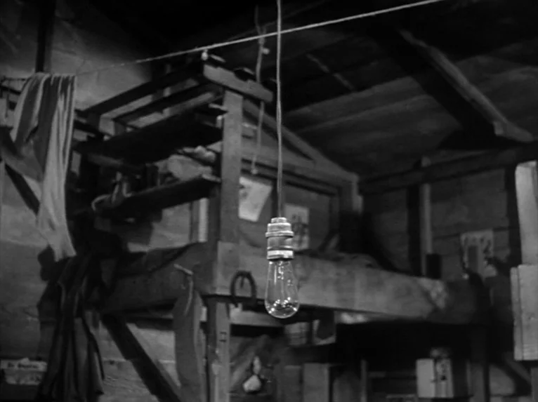 Stalag 17 (1953) movie still: wide — A wooden shack interior features a bunk bed frame with miscellaneous clothing items draped nearby. A single…