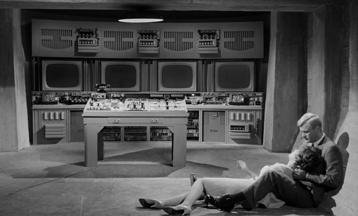 The 1,000 Eyes of Dr. Mabuse (1960) movie still: wide — A minimalist industrial control room features four CRT monitors built into a wall console. A…