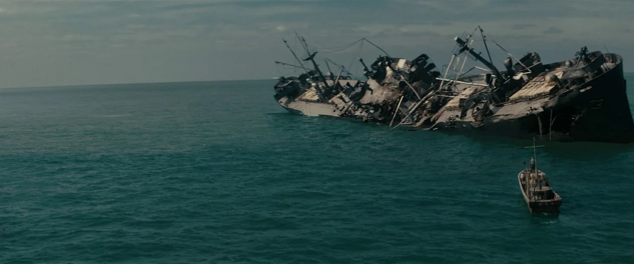 Godzilla Minus One (2023) movie still: wide — A rusted, severely damaged shipwreck lies partially submerged in the vast open ocean. A small wooden…