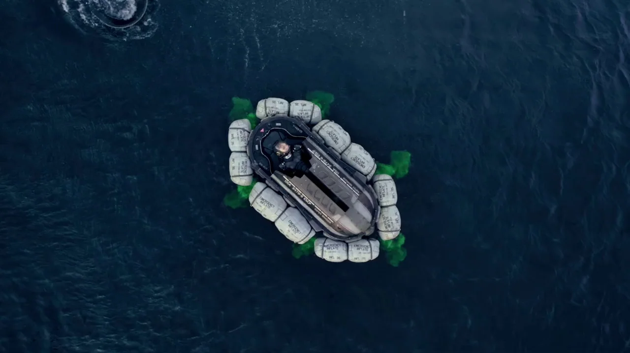 Pacific Rim (2013) movie still: wide — An aerial view shows a person in a small emergency raft on open water. Green dye tracer clouds disperse into…