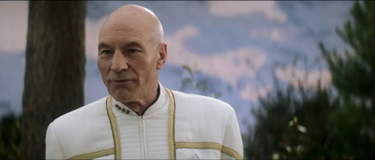 Star Trek: Nemesis (2002) movie still: medium — A man stands outdoors in front of out-of-focus trees and a light sky. The man wears a formal white…