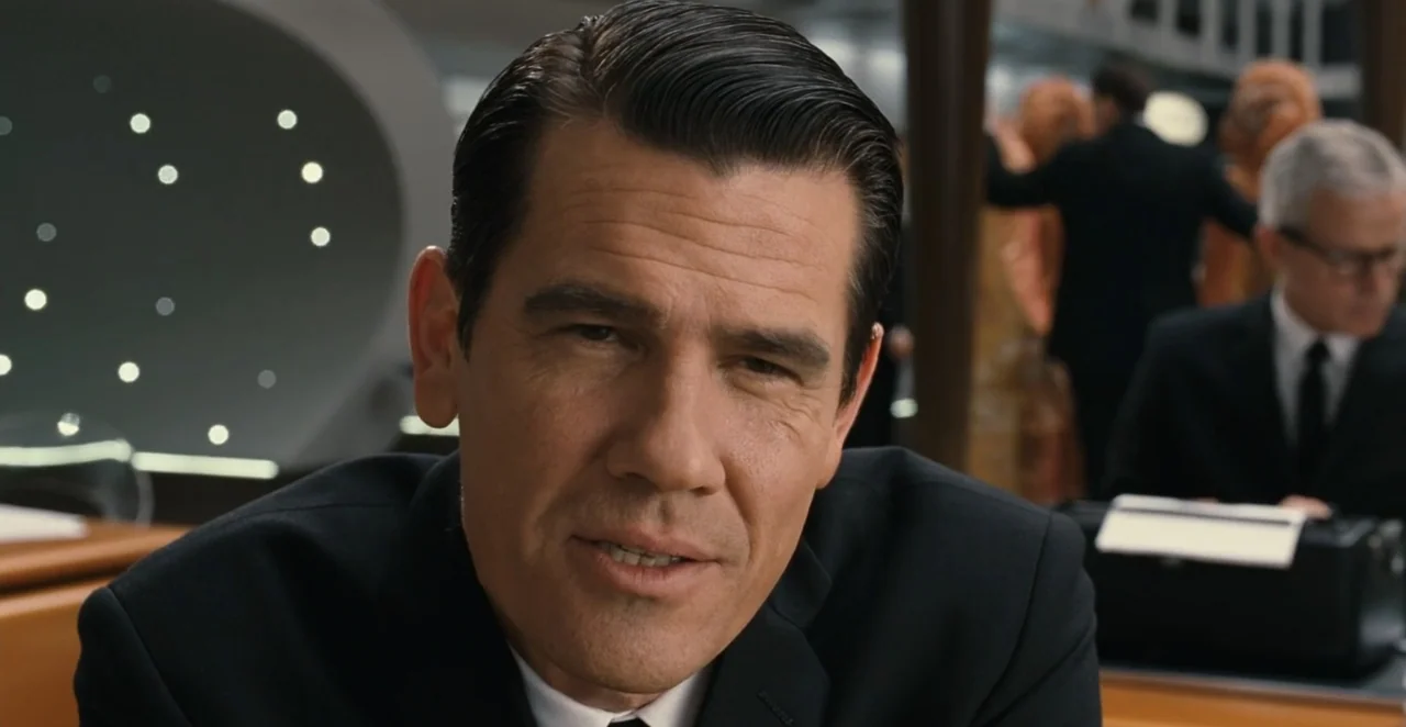 Men in Black 3 (2012) movie still: closeup — A 1960s-style office with modern desks and out-of-focus background activity. A middle-aged man in a…