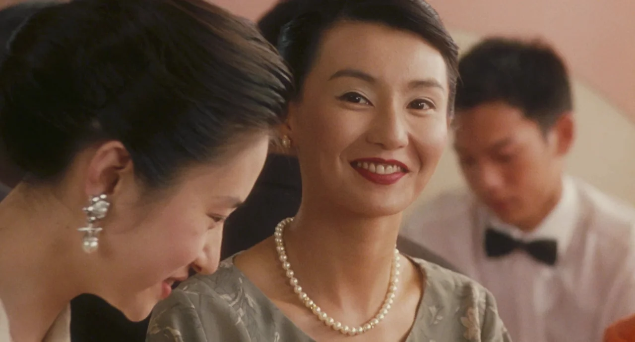 Comrades: Almost A Love Story (1996) movie still: medium — A group of people are seated at a table in a dimly lit restaurant. A woman with dark hair…