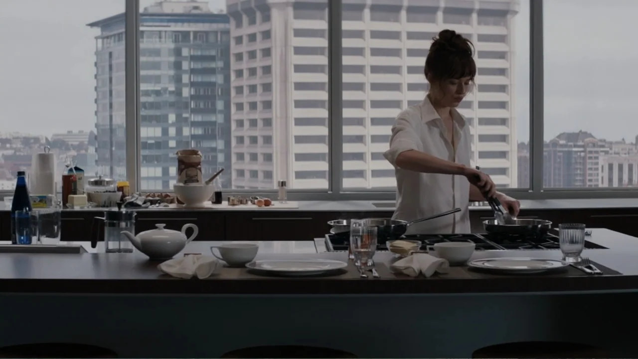 Fifty Shades of Grey (2015) movie still: medium — A minimalist high-rise kitchen features clean countertops and expansive windows looking out onto…
