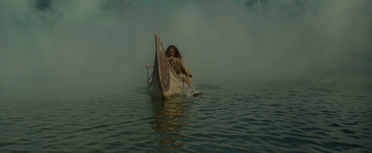 The Last of the Mohicans (1992) movie still: wide — A man in a canoe glides across a calm, expansive lake covered in fog. The surrounding landscape…