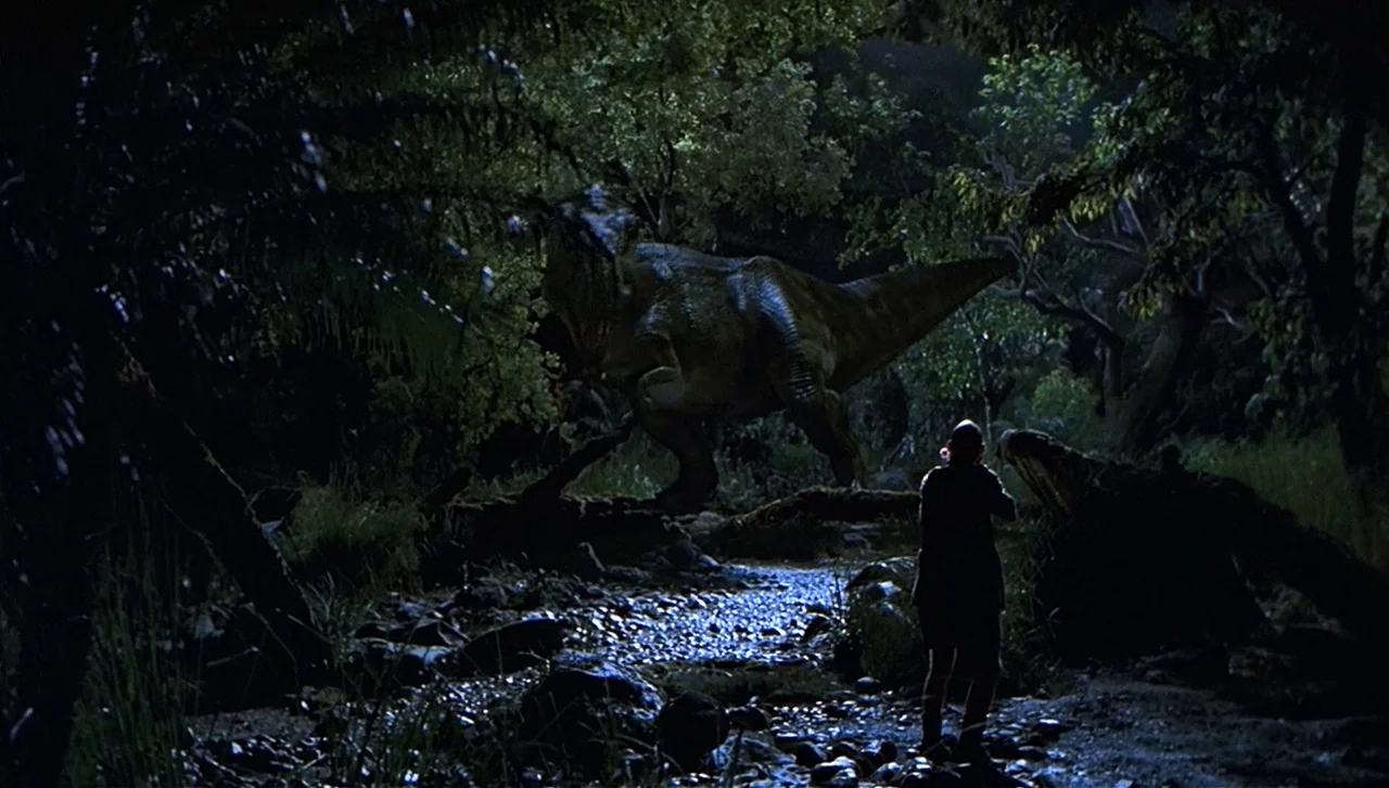The Lost World: Jurassic Park (1997) movie still: wide — A dark, dense woodland at night features a shallow, rock-filled stream bed. A large…