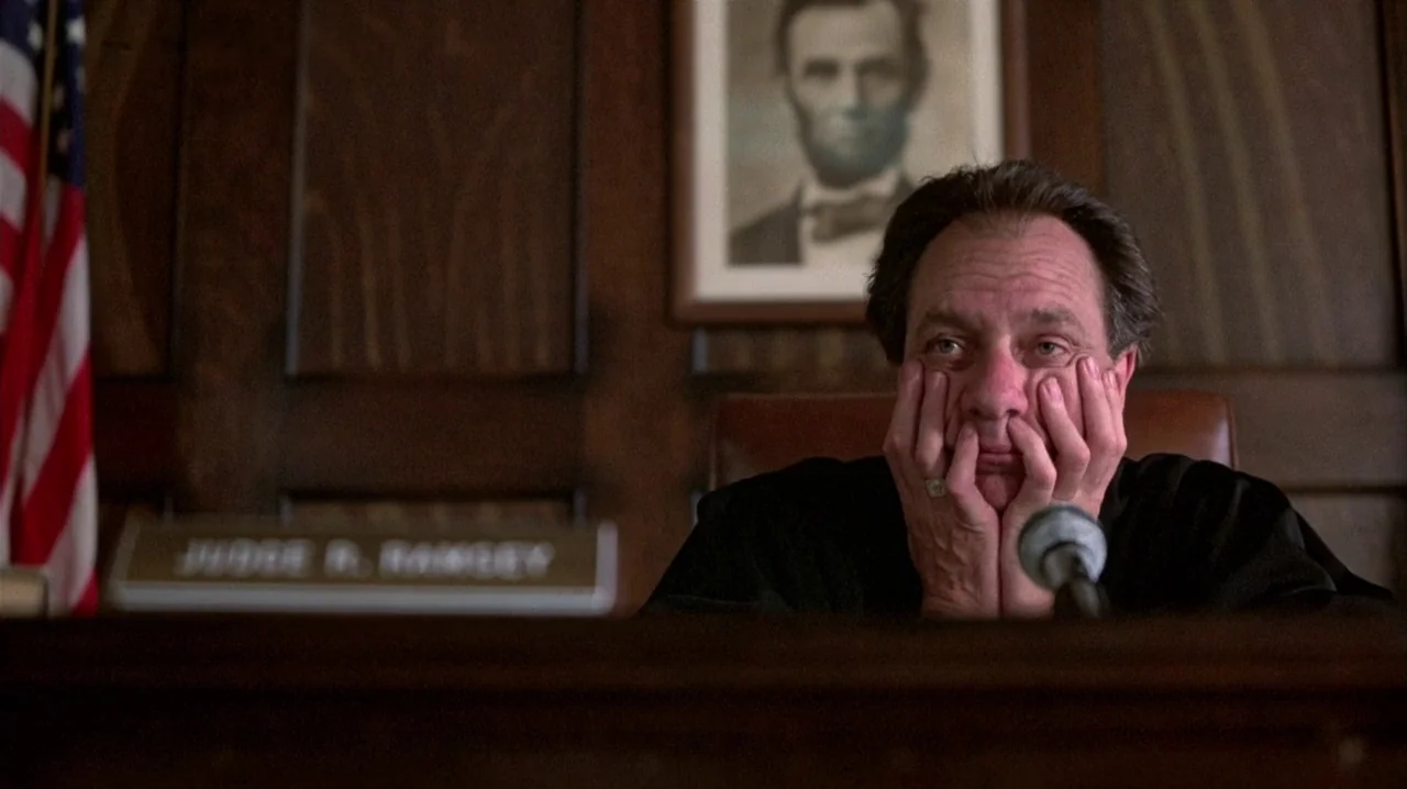 Thief (1981) movie still: medium — A wood-paneled office features an American flag and a framed portrait of Abraham Lincoln. The judge sits behind…