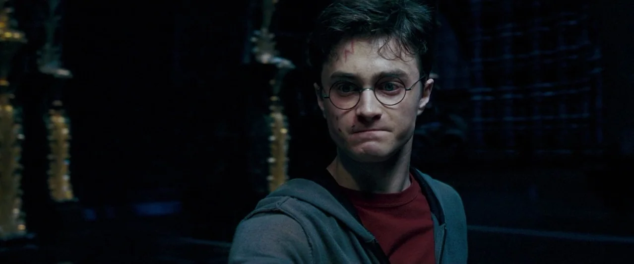 Harry Potter & The Order of the Phoenix (2007) movie still: closeup — A dimly lit, stone-walled interior with blurred gothic architectural elements…