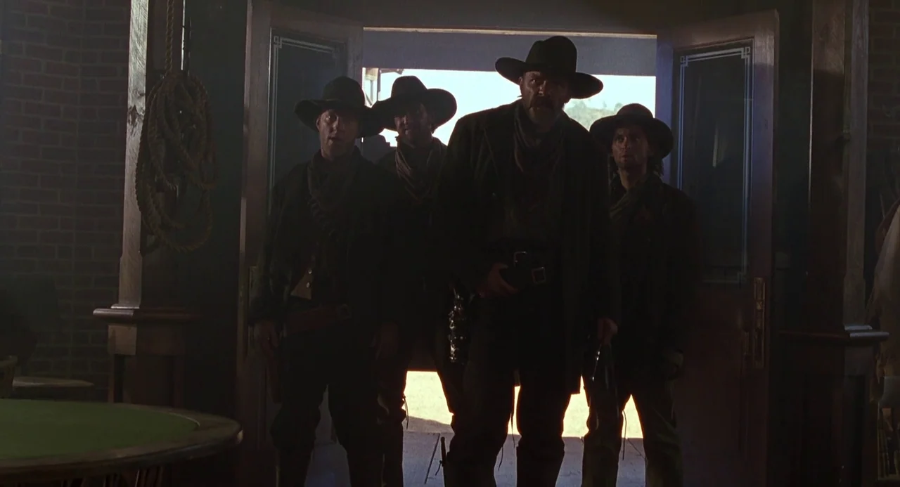 Back To The Future Part III (1990) movie still: fullbody — A dimly lit western saloon interior features red brick walls and wooden architecture.…