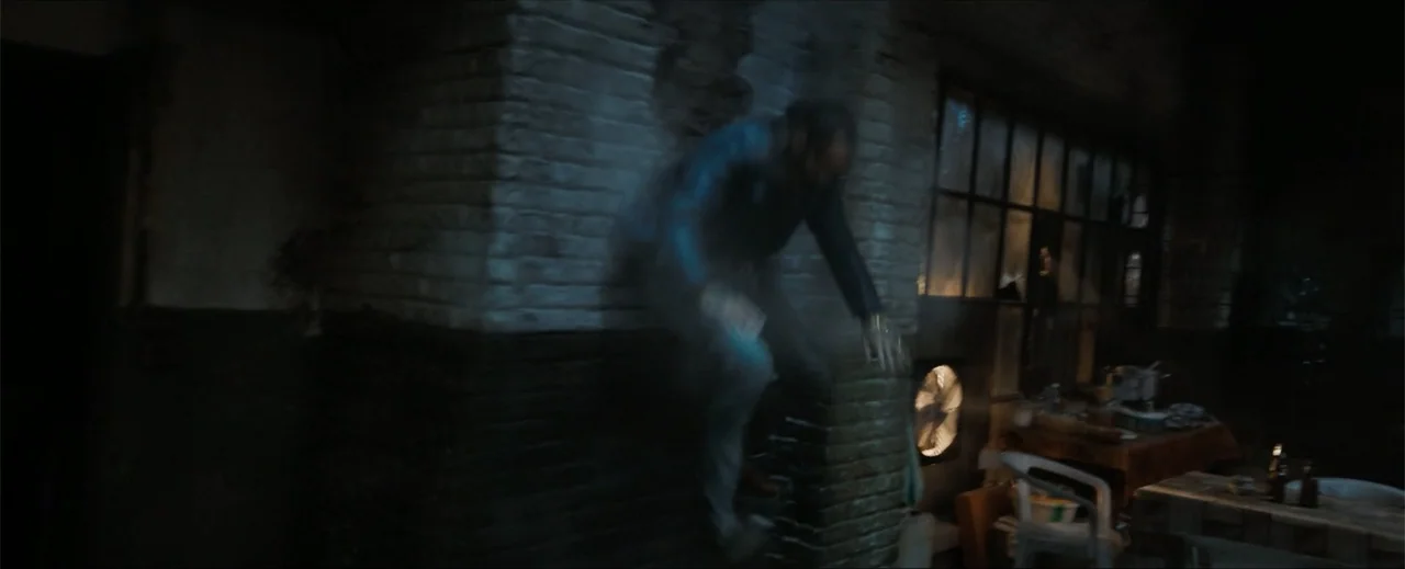 Venom: The Last Dance (2024) movie still: medium — A dimly lit room with exposed brick walls and scattered furniture in the background. A man lunges…