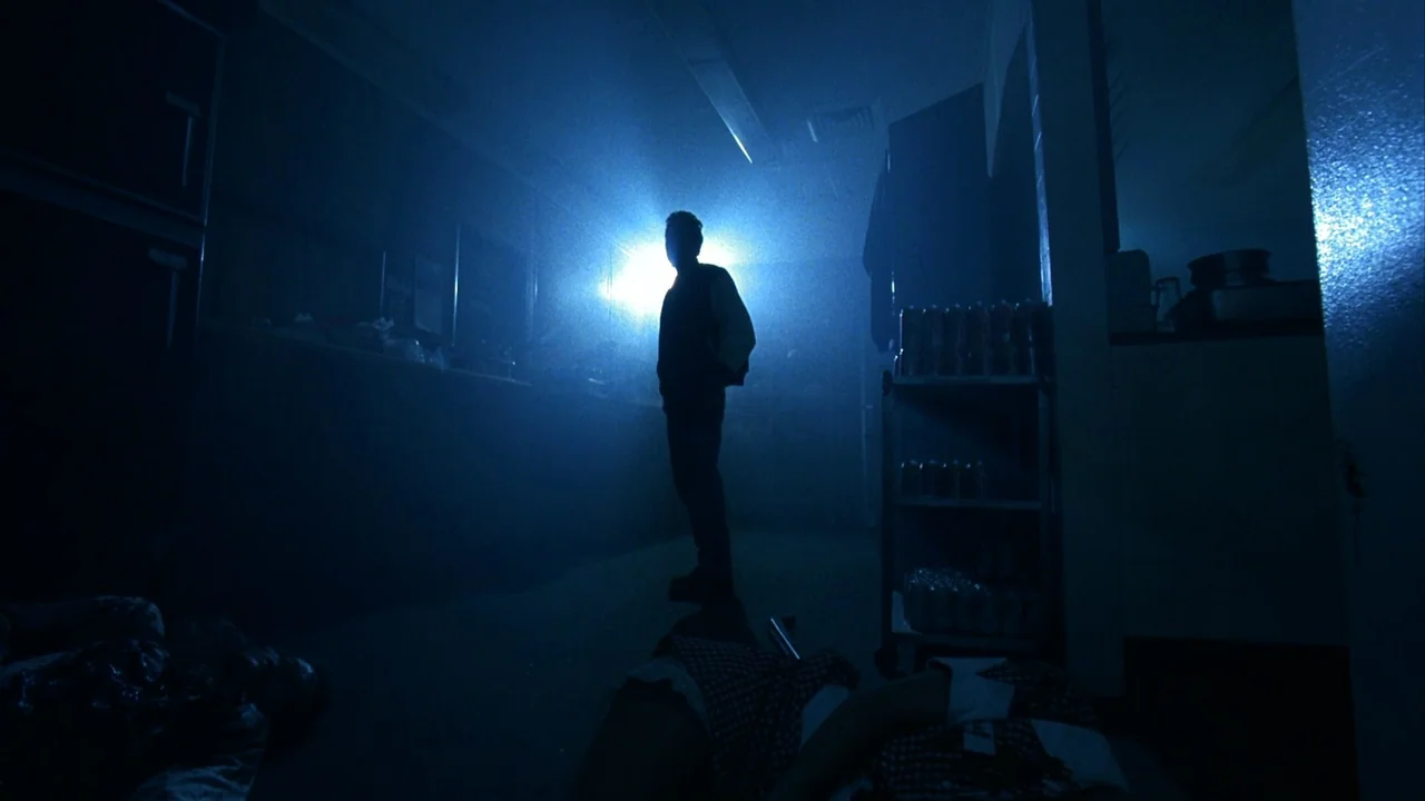 Jason Goes To Hell (1993) movie still: wide — A convenience store interior is filled with blue haze and artificial backlight. A man stands in the…