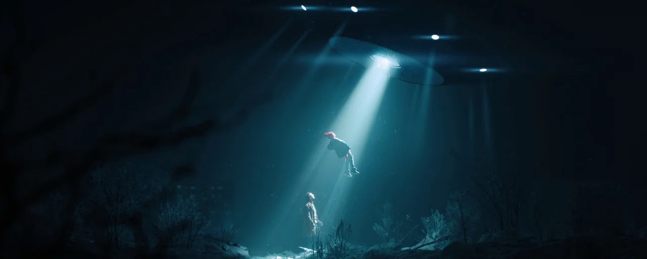 Petrov’s Flu (2021) movie still: wide — A dark, frost-covered field is illuminated from above by a mysterious metallic disc. A boy levitates toward…