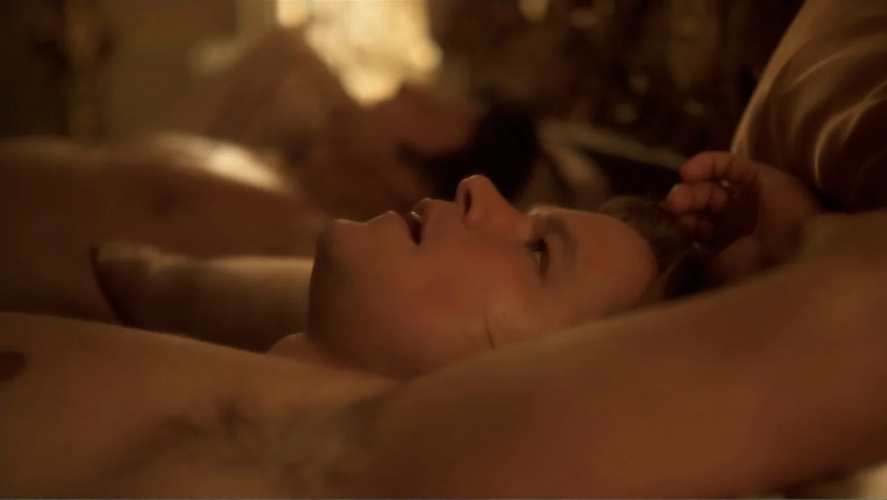 Behind the Candelabra (2013) movie still: closeup — A dark bedroom interior shows two men lying in a bed together at night. A man rests his head on…