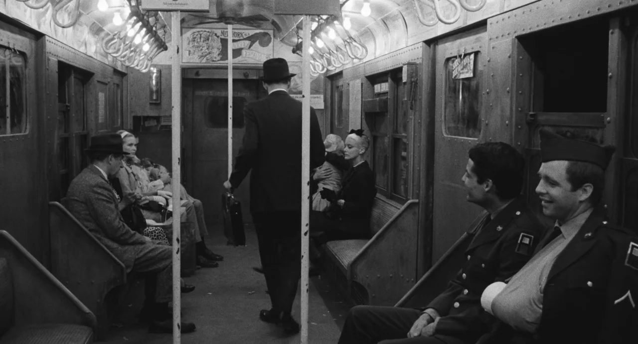 The Incident (1967) movie still: wide — An interior view of a 1940s subway train with passengers seated on opposite sides. A man in a suit and hat…