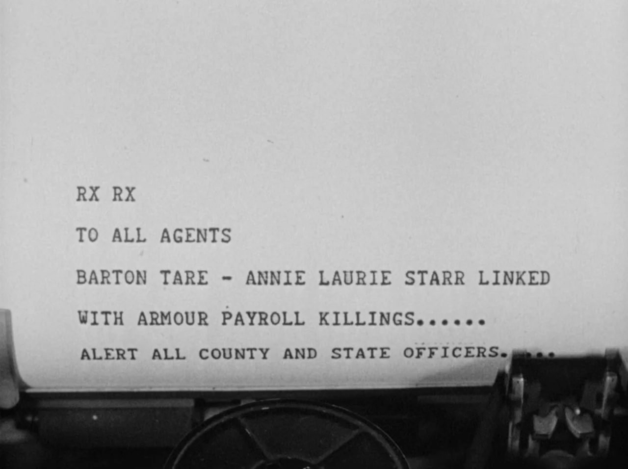 Gun Crazy (1950) movie still: closeup — A close-up of a white document inside a vintage typewriter. The paper displays typed police text regarding…