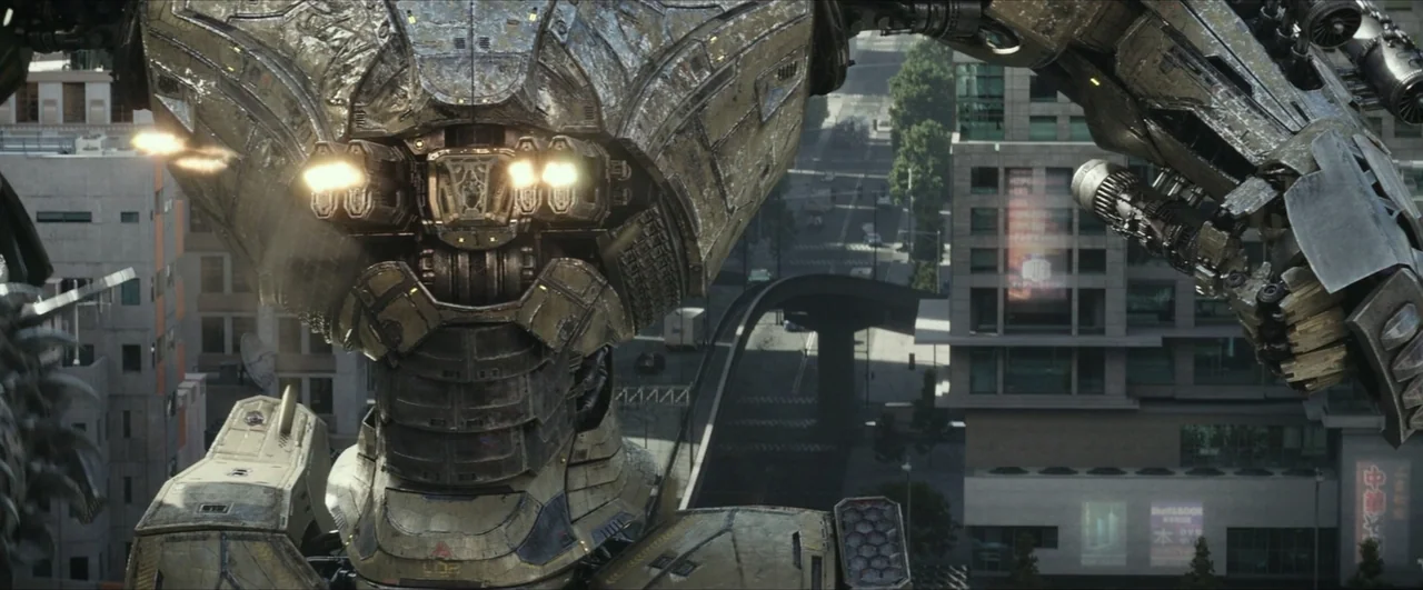 Pacific Rim: Uprising (2018) movie still: medium — A gargantuan mechanical robot stands amidst a modern urban landscape with paved roads. The metal…