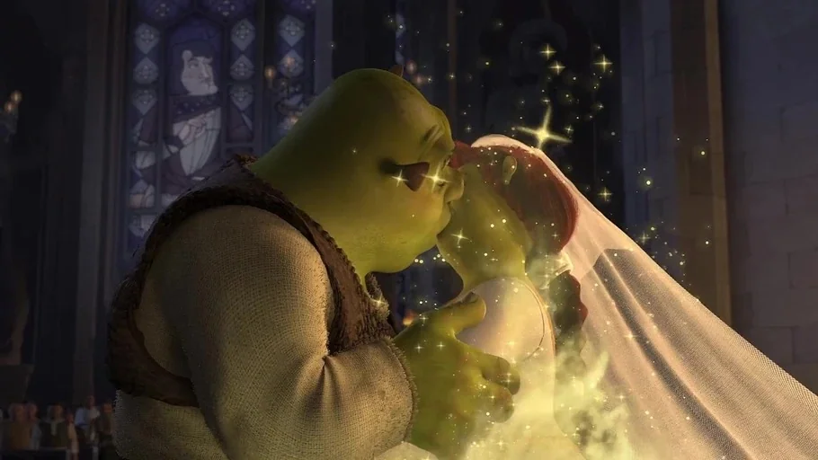 Shrek (2001) movie still: medium — A stone interior with stained glass panels serves as the backdrop for a ceremony. An ogre and his bride embrace…