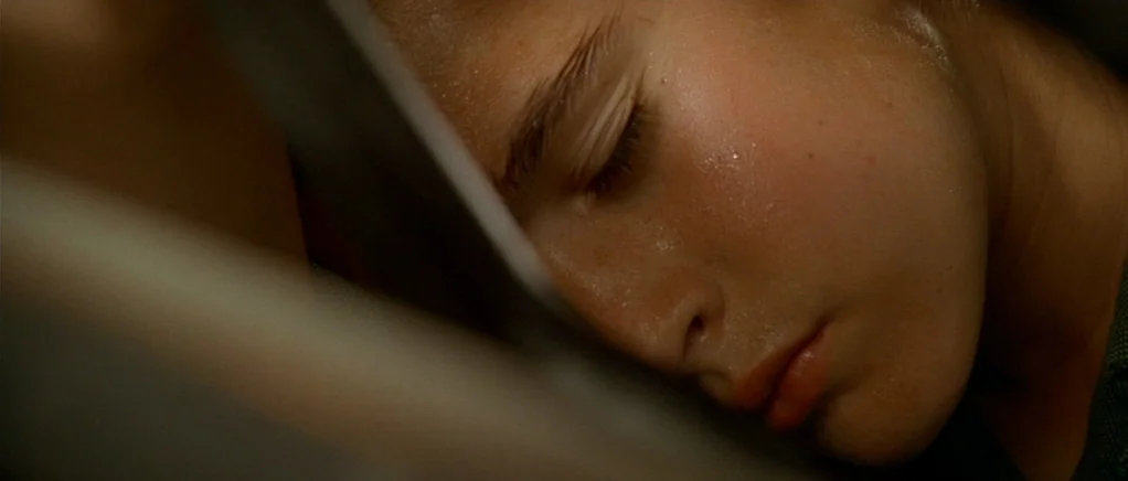 King of the Hill (1993) movie still: closeup — A close-up view of a person sleeping in a dimly lit room. The subject's face is illuminated by a warm…