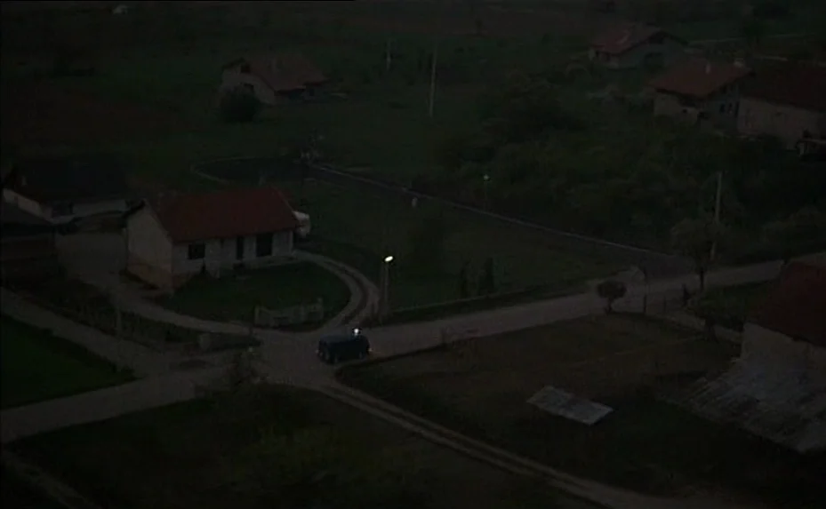 The Woman Next Door (1981) movie still: establishing — A rural village landscape sits under a dark night sky with scattered small houses. A single…