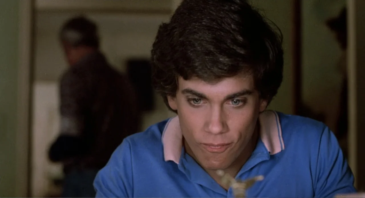 Harry and the Butler (1961) movie still: closeup — A dimly lit room provides the backdrop for a young man in a polo shirt. He holds a small object…