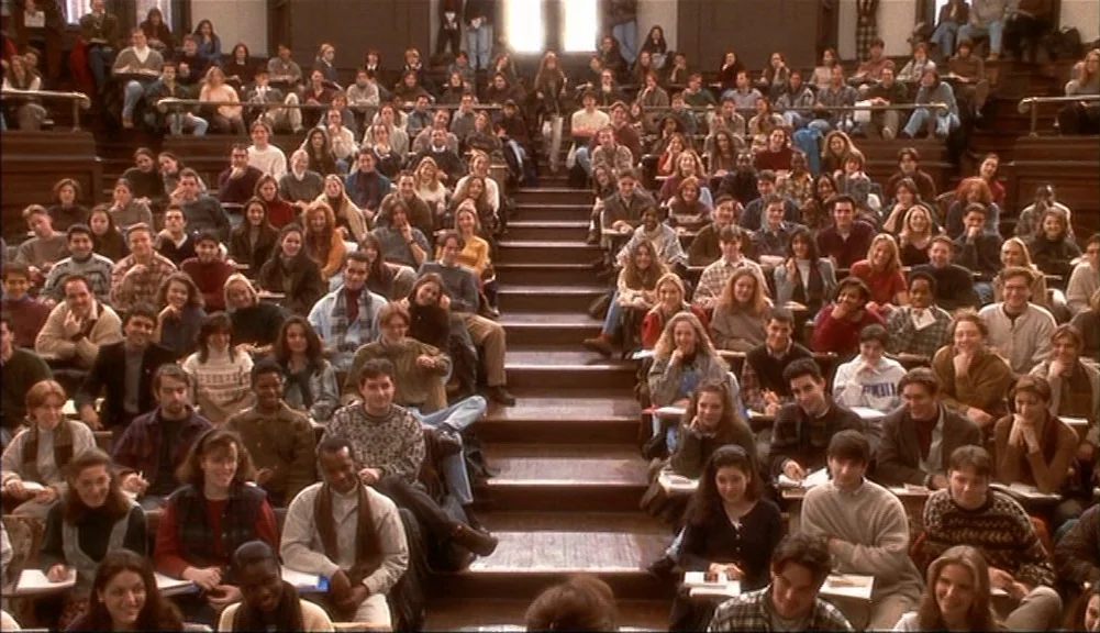 The Mirror Has Two Faces (1996) movie still: wide — A crowded university lecture hall features tiered wooden seating filled with students. Many…
