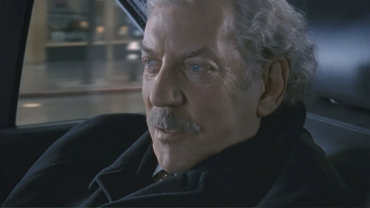 The Art of War (2000) movie still: closeup — The interior of a moving vehicle at night with blurred city lights visible outside. An older man with a…