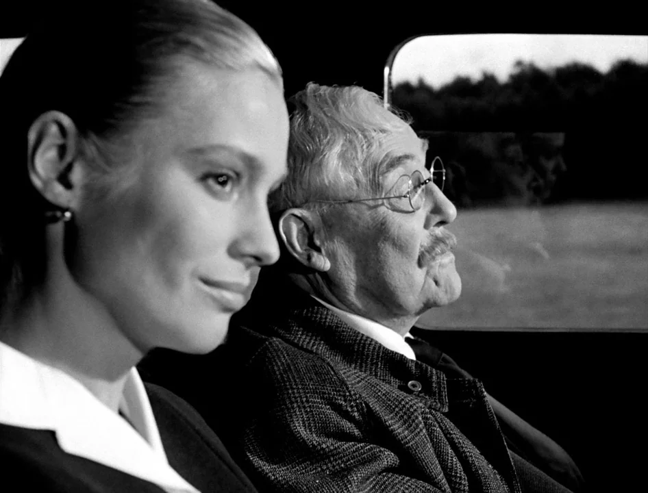 Wild Strawberries (1957) movie still: medium — A woman and an elderly man sit next to each other inside a vehicle. They are positioned to look out a…