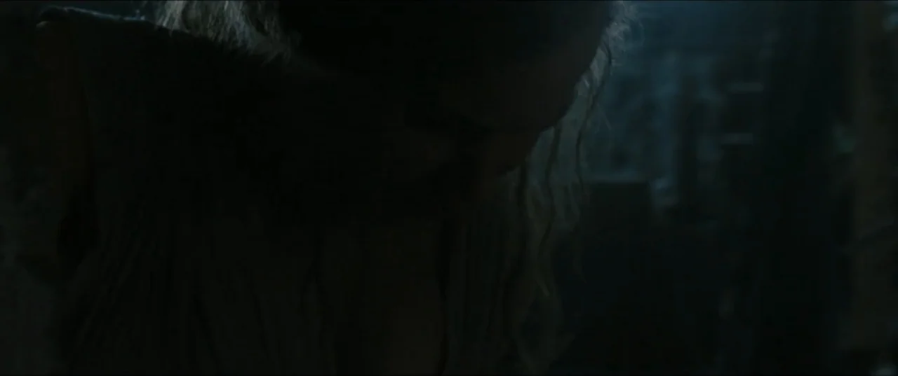 mother! (2017) movie still: closeup — A dark, minimally lit interior space with textured walls and faint ambient shadows. A woman with long light…