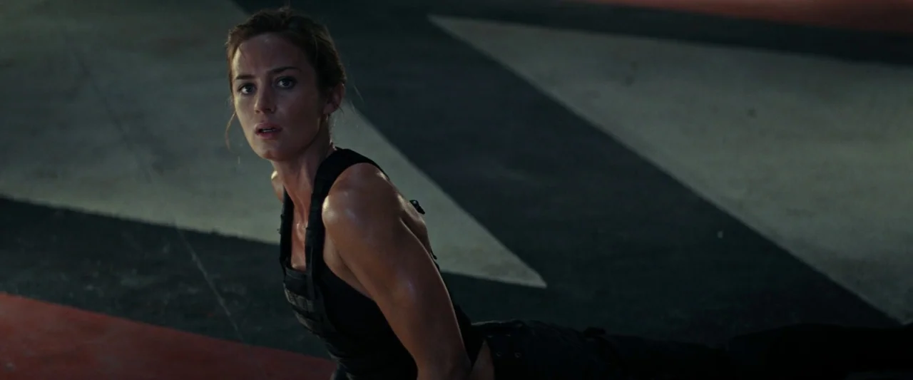 Edge of Tomorrow (2014) movie still: medium — A large concrete floor with painted geometric white and red stripes on a dark background. A woman in…