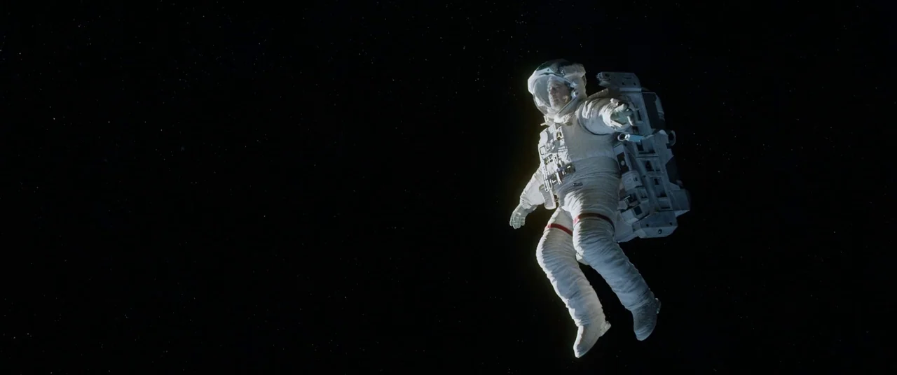 Gravity (2013) movie still: fullbody — An astronaut drifts through the expansive, star-dusted darkness of deep space. The subject is suspended…