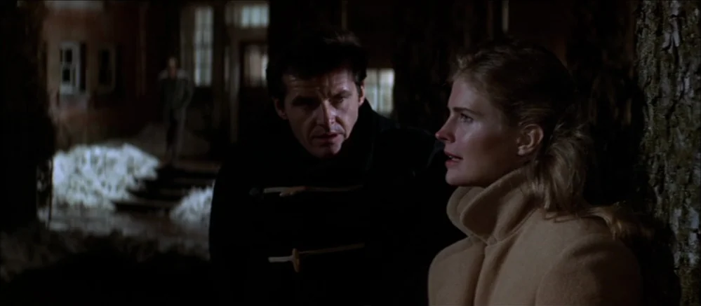 Carnal Knowledge (1971) movie still: medium — A dark, nighttime outdoor setting with thick trees flanking the subjects. A man in a dark coat and a…