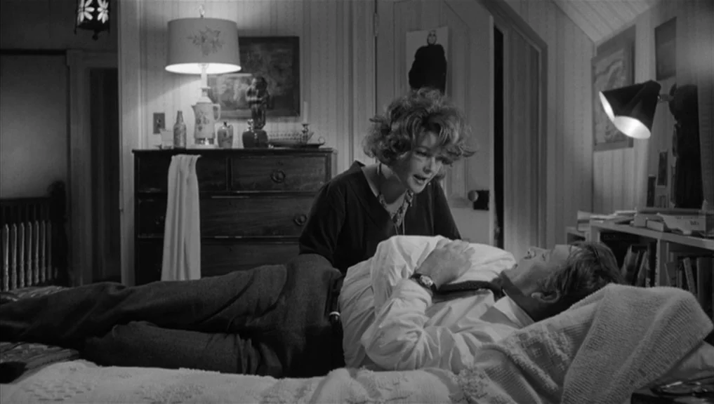 Who’s Afraid Of Virginia Woolf? (1966) movie still: medium — A cluttered 1960s bedroom features a wooden dresser adorned with lamps and small…