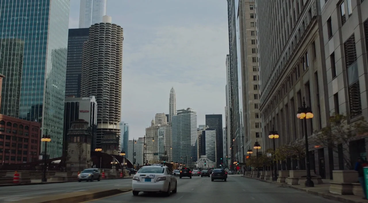 The Big Sick (2017) movie still: establishing — An urban thoroughfare in Chicago with skyscrapers including the Marina City complex. Multiple cars…