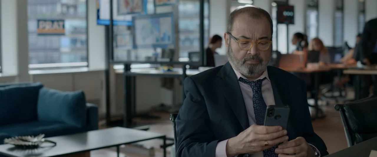 Doublespeak (2021) movie still: medium — A modern, bright office features glass partitions and workstations with employees visible in distance. A…